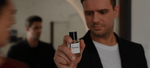 Mann hält ein Parfum in der Hand und ist umgeben von zwei Personen